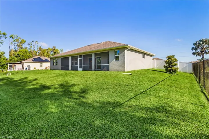 Back of house with a fenced backyard, a sunroom, and stucco siding