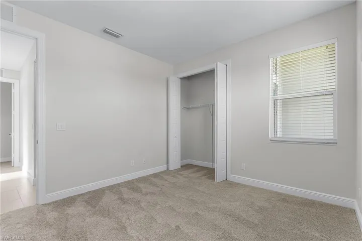 Unfurnished bedroom with light colored carpet and a closet