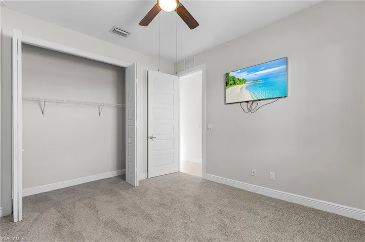 Unfurnished bedroom with light colored carpet, a closet, and a ceiling fan
