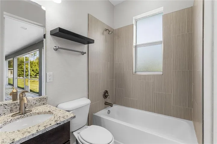 Bathroom featuring shower / tub combination, a textured wall, and vanity
