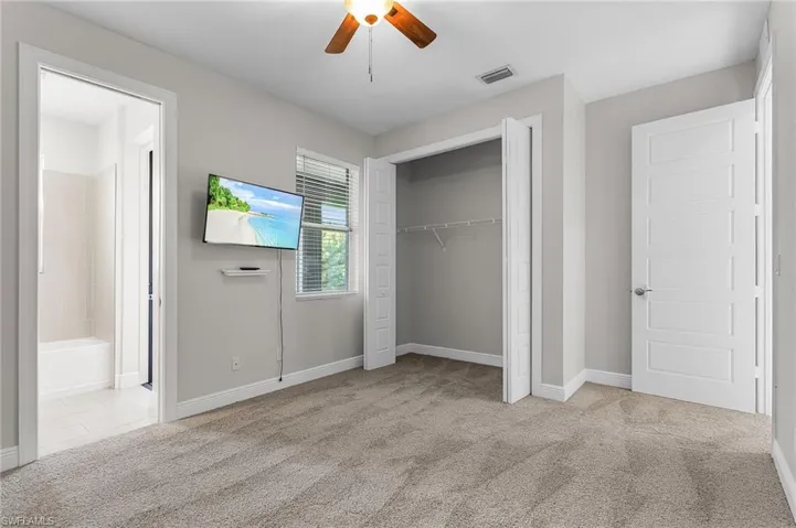 Unfurnished bedroom with light colored carpet, a closet, ceiling fan, and ensuite bath