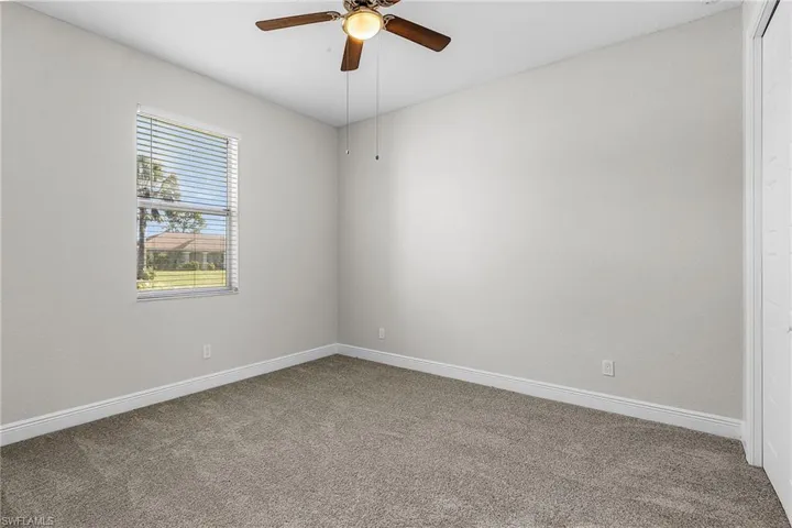Carpeted spare room with baseboards and a ceiling fan