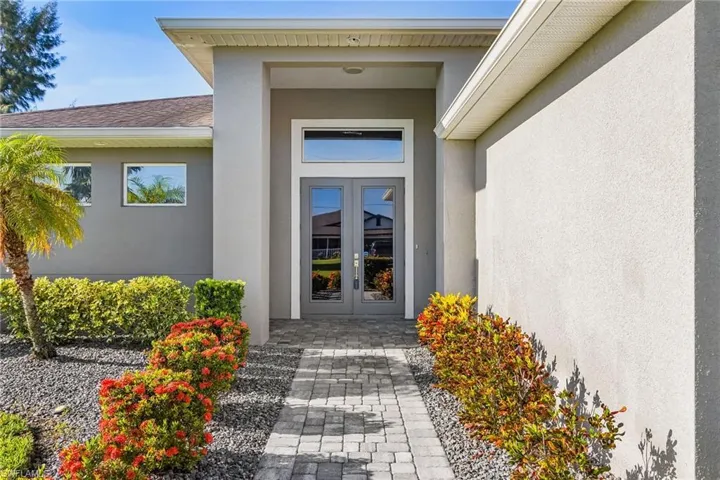 Property entrance with french doors, stucco siding, and a shingled roof