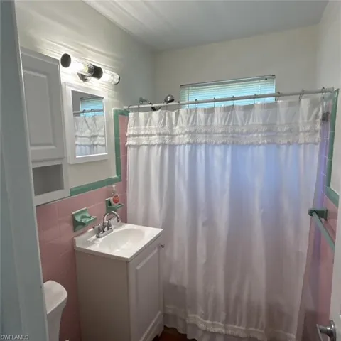 Bathroom with tile walls, vanity, healthy amount of natural light, and shower / tub combo