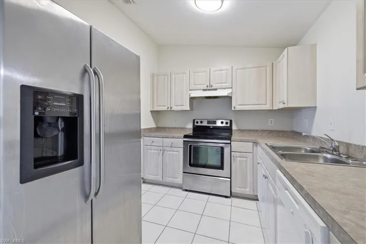 Kitchen featuring a side-by-side stainless steel refrigerator with an external ice/water dispenser, white cabinetry, a stainless steel range with a ventilation hood, laminate countertops, and a double basin stainless steel sink