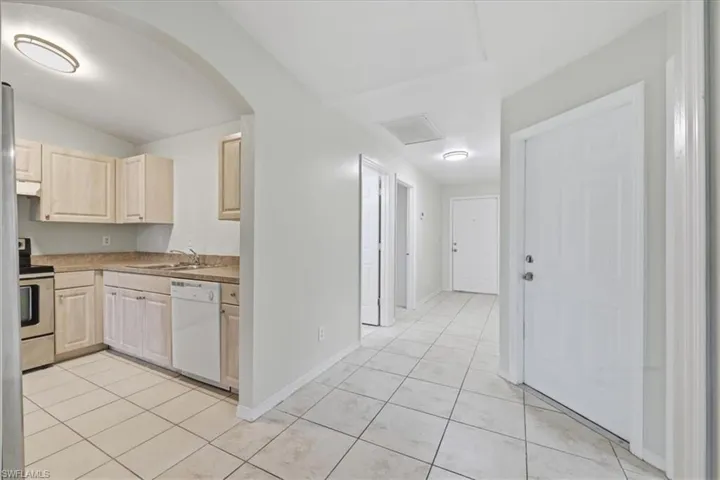 Open-concept kitchen featuring light-toned cabinetry, stainless steel appliances, and a tiled floor