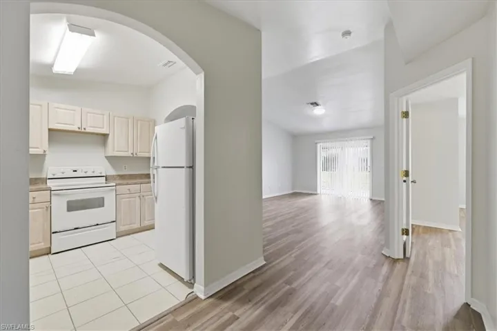 Kitchen featuring light wood-finish cabinetry, white appliances, and tiled flooring