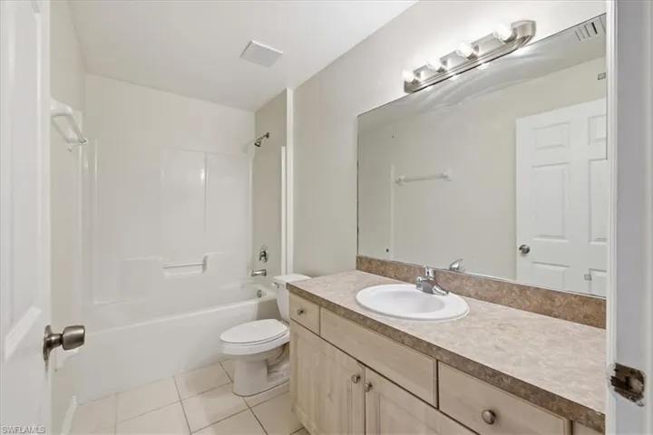 Bathroom featuring a vanity with an integrated sink, a large mirror, and a full-size bathtub with a shower