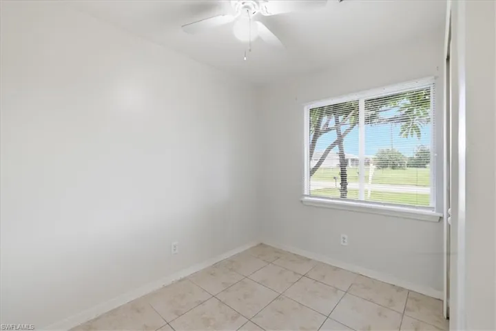 Bright room featuring a window with white blinds, neutral wall paint, and tile flooring