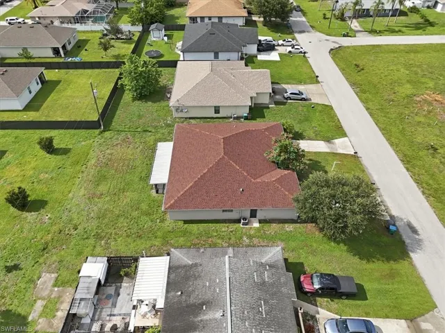 Single-story residence with a red-shingled roof, light-colored siding, and a concrete driveway