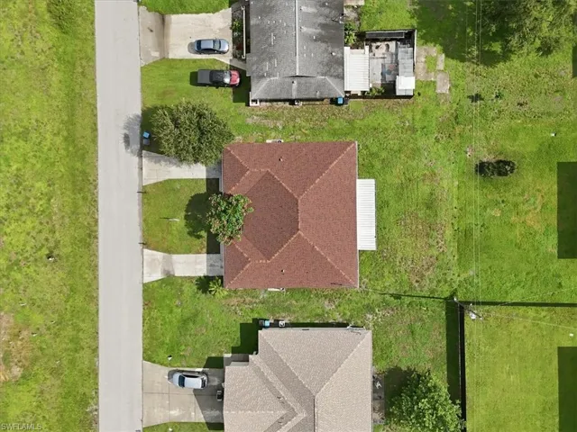 Property featuring a brown shingle roof, a concrete driveway, and a partially grassed lot