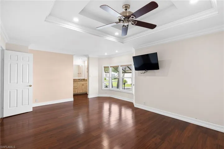 Unfurnished bedroom with hardwood / wood-style floors, crown molding, and a tray ceiling
