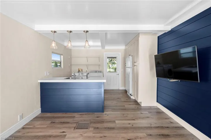 Kitchen with a wealth of natural light, beam ceiling, hardwood / wood-style floors, and white refrigerator