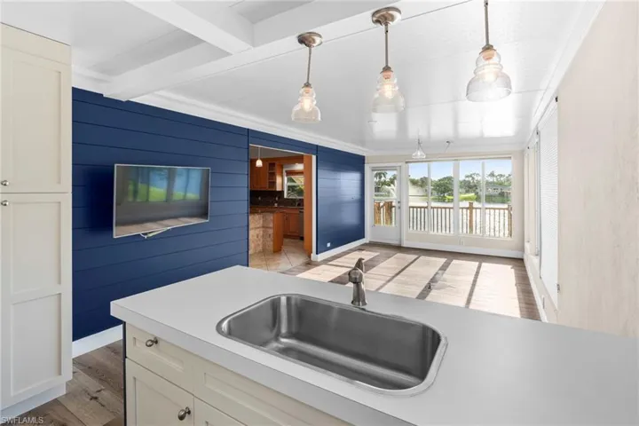 Kitchen featuring sink, light hardwood / wood-style floors, white cabinets, and pendant lighting