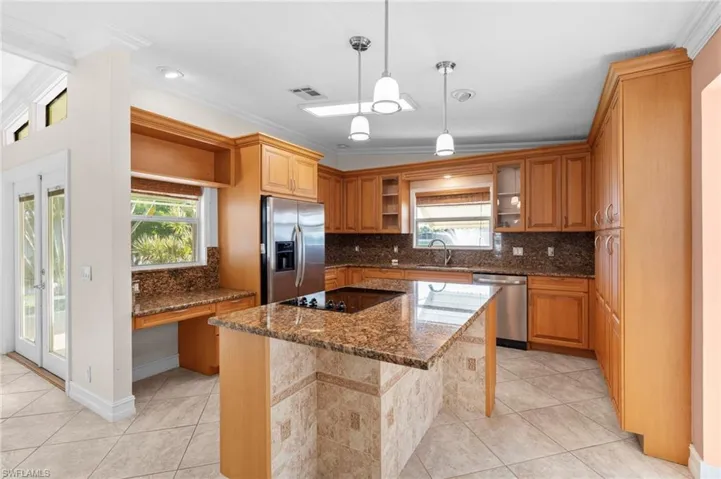 Kitchen featuring appliances with stainless steel finishes, backsplash, light tile patterned floors, a kitchen island, and a breakfast bar area