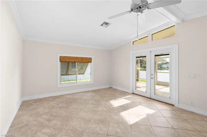 Tiled spare room with ceiling fan, french doors, and lofted ceiling with beams