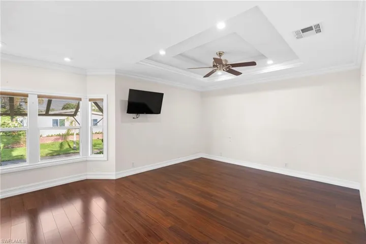Spare room featuring ceiling fan, hardwood / wood-style flooring, ornamental molding, and a tray ceiling