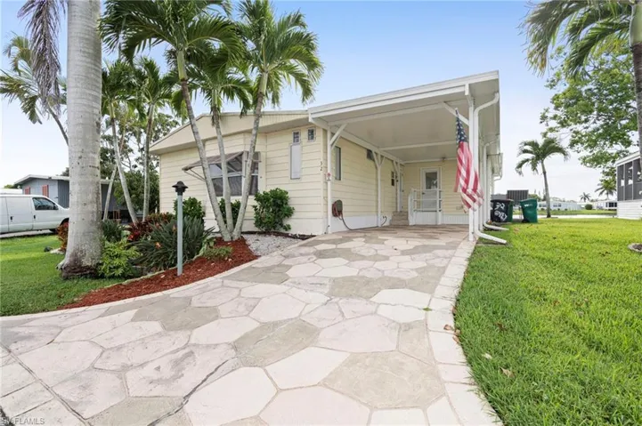 View of front of property featuring a front lawn and a carport