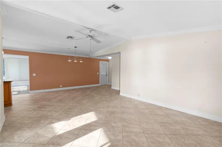Spare room featuring ceiling fan, crown molding, light tile patterned floors, and lofted ceiling with beams