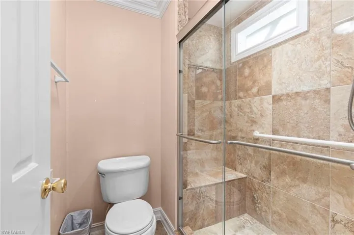 Bathroom with an enclosed shower, toilet, and crown molding