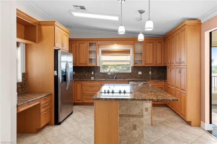 Kitchen featuring light tile patterned floors, a center island, stainless steel appliances, and ornamental molding