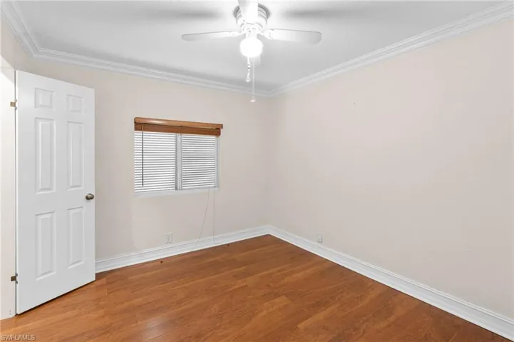 Empty room with ceiling fan, ornamental molding, and wood-type flooring