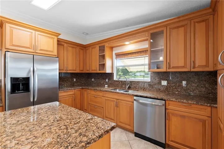 Kitchen with appliances with stainless steel finishes, decorative backsplash, stone countertops, and sink