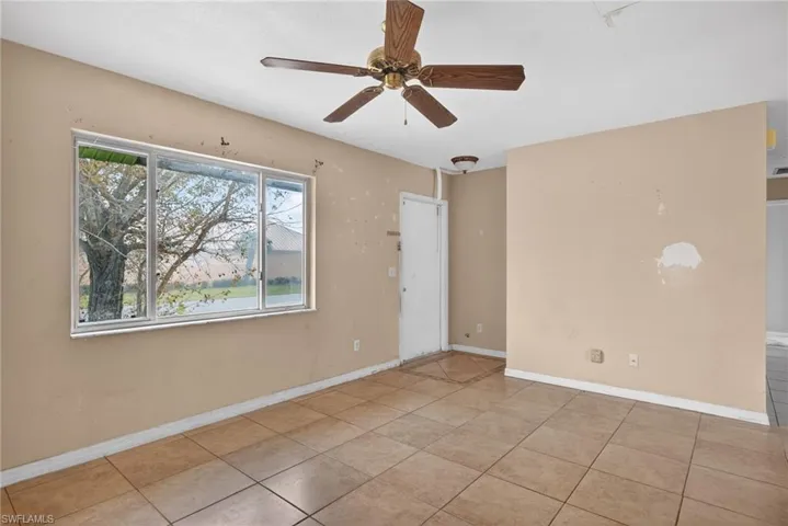 Tiled spare room featuring ceiling fan and baseboards