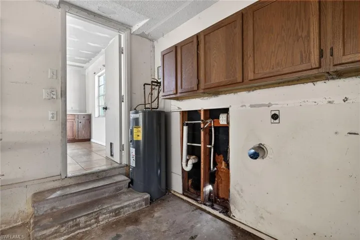 Laundry room with electric water heater, unfinished concrete flooring, cabinet space, and hookup for an electric dryer