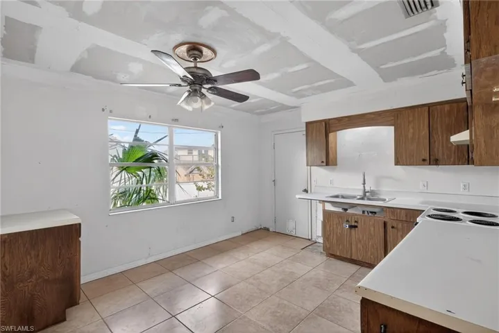 Kitchen with light countertops, ceiling fan, wood finish cabinets, and light tile patterned floors