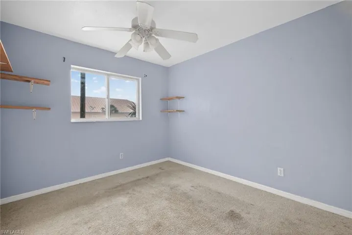 Carpeted empty room featuring ceiling fan and baseboards
