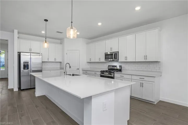 Kitchen features natural gas appliances, oversized island, quartz countertops, over and under cabinet lighting, and walk-in pantry.