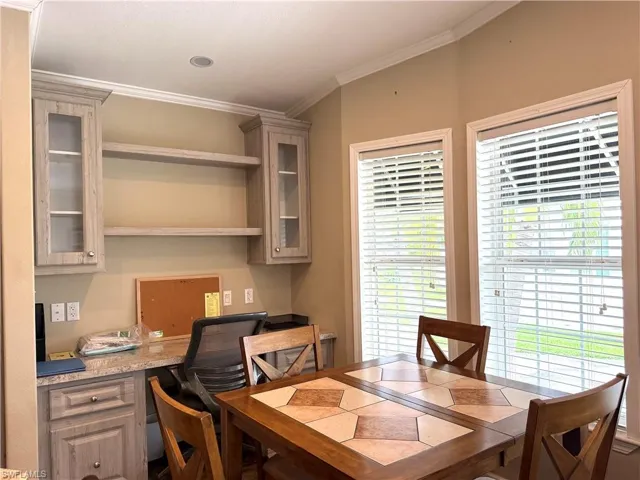Built-in desk area featuring wood-finish cabinetry with glass inserts, open shelving, and a light-colored countertop