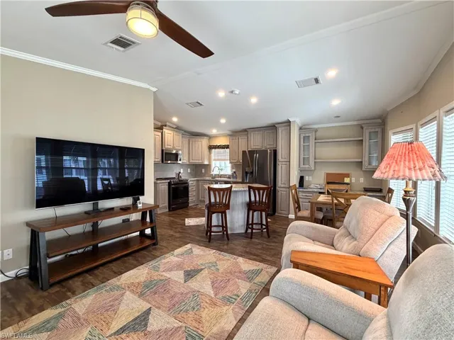 Open-concept living area with wood-finish flooring, recessed lighting, and crown molding
