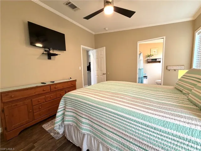 Wood-finish flooring with crown molding, ceiling fan, and wall-mounted television