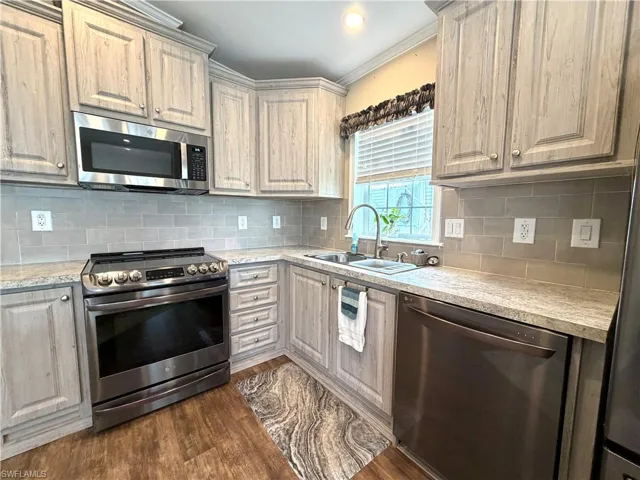 Kitchen featuring stainless steel appliances, wood-finish cabinetry, light-colored countertops, and a subway tile backsplash