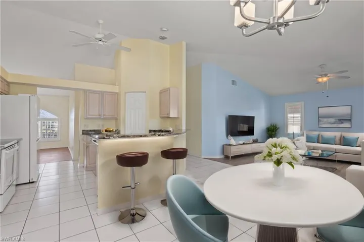 Virtually Staged Dining area with high vaulted ceiling, ceiling fan with notable chandelier, and light hardwood / wood-style flooring