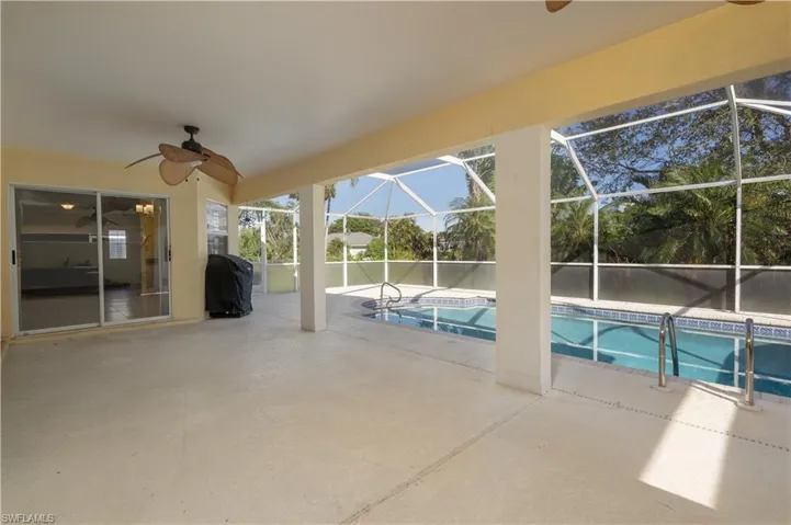 View of swimming pool featuring grilling area, glass enclosure, a patio, and ceiling fan
