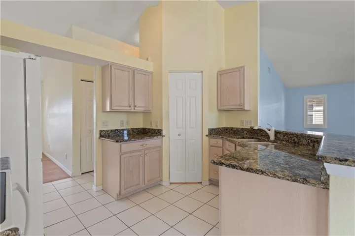 Kitchen with dark stone countertops, light brown cabinets, and sink