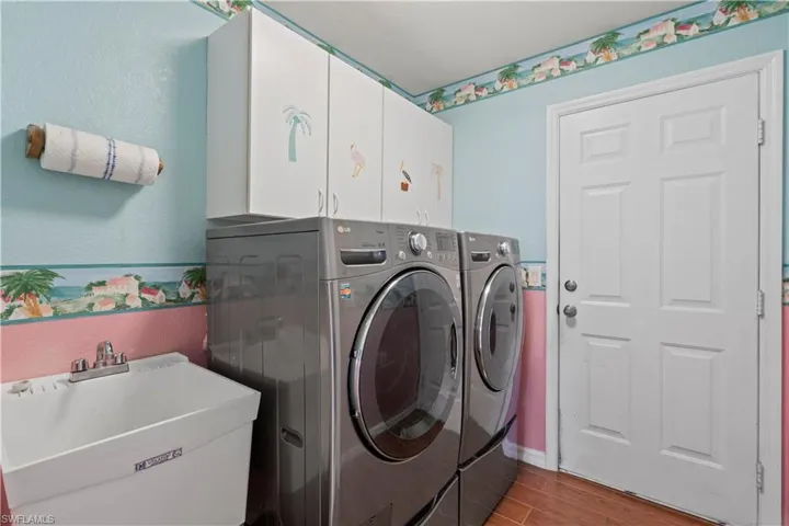 Laundry area featuring light wood-type flooring, separate washer and dryer, cabinets, and sink