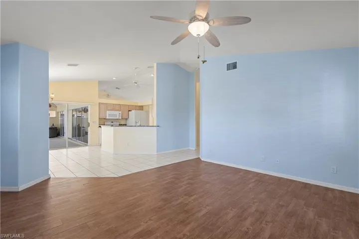 Empty room with light wood-type flooring, ceiling fan, and high vaulted ceiling