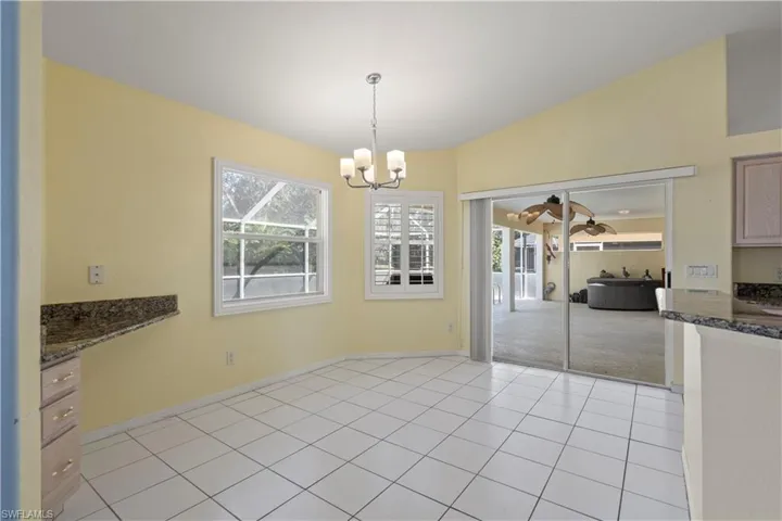 Unfurnished dining area featuring light tile patterned floors, an inviting chandelier, and vaulted ceiling