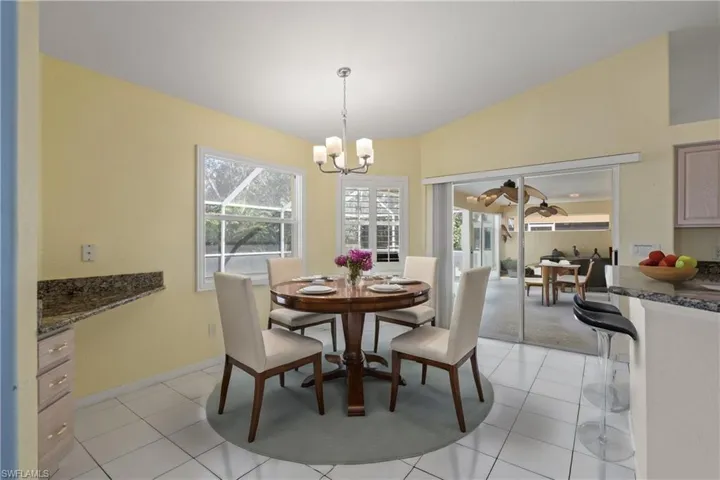 Dining room featuring a chandelier, a wealth of natural light, light tile patterned floors, and lofted ceiling