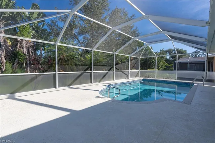 View of swimming pool with a patio and glass enclosure