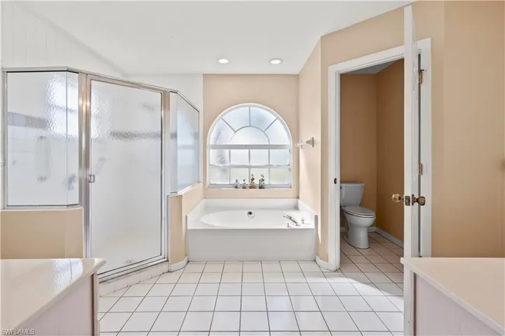 Bathroom featuring toilet, shower with separate bathtub, and tile patterned floors