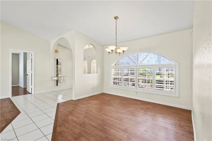 Unfurnished dining area featuring vaulted ceiling, an inviting chandelier, and light tile patterned flooring