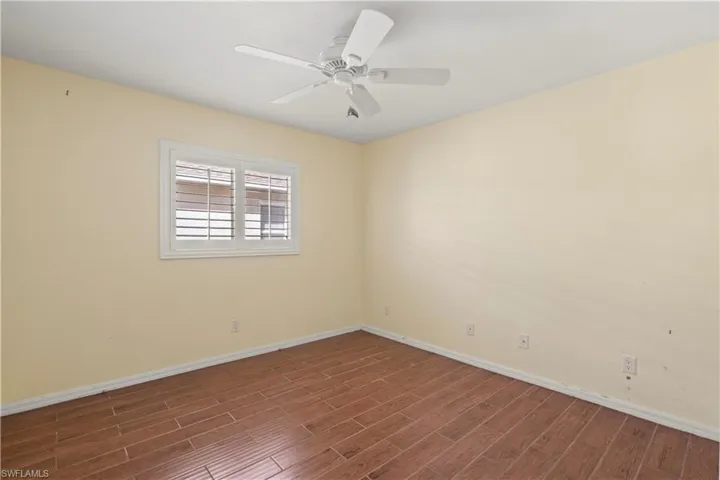 Unfurnished room with dark wood-type flooring and ceiling fan
