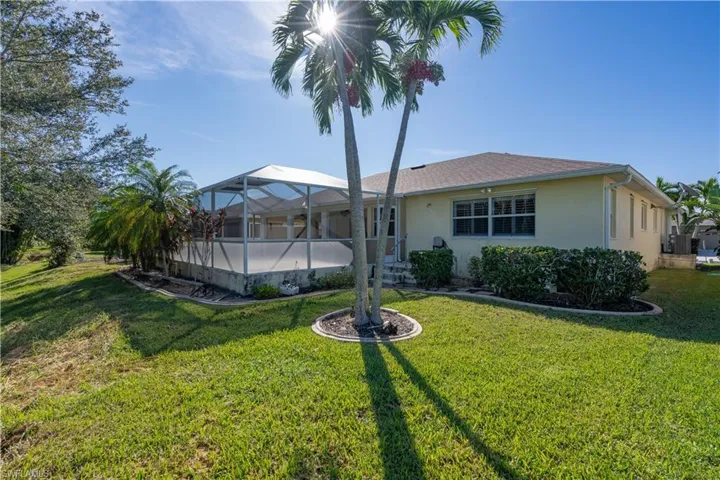 Back of property featuring a lanai and a lawn
