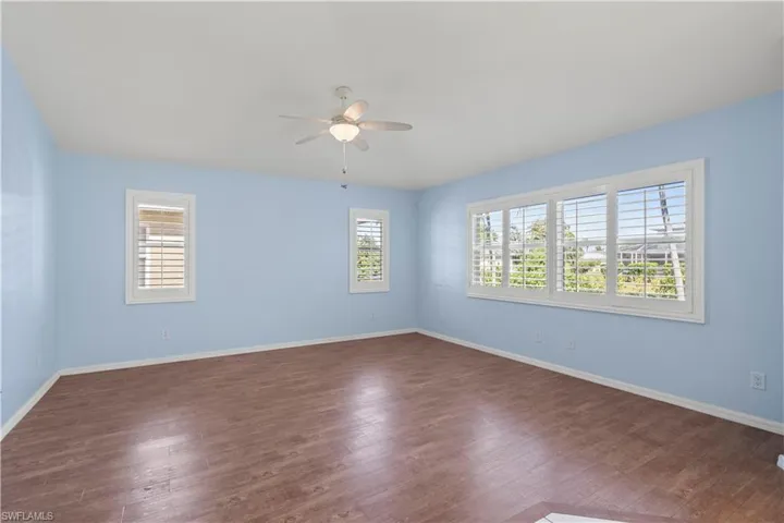 Spare room featuring ceiling fan, plenty of natural light, and dark hardwood / wood-style floors