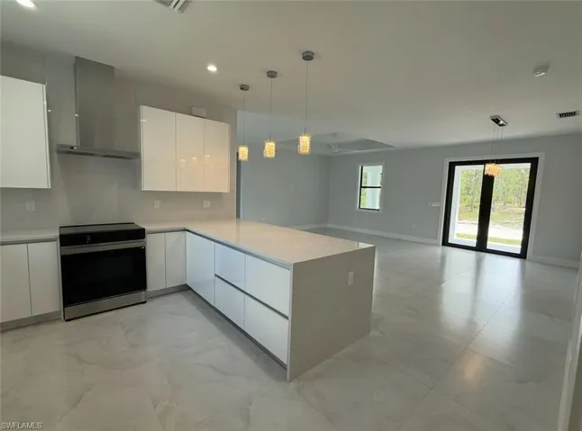 Kitchen with light countertops, marble finish floor, modern cabinets, electric stove, and wall chimney range hood